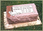 monument horizontal to the ground that is several inches think with a beveled-slanted top with rough hewn sides with text and image edtched in the top